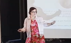 kitty in red dress and pink shirt on stage speaking 