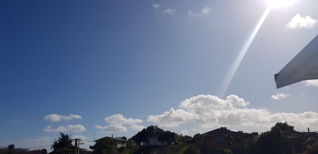 blue skies with a small fluffy cloud and sunshine rays pouring in from the right.